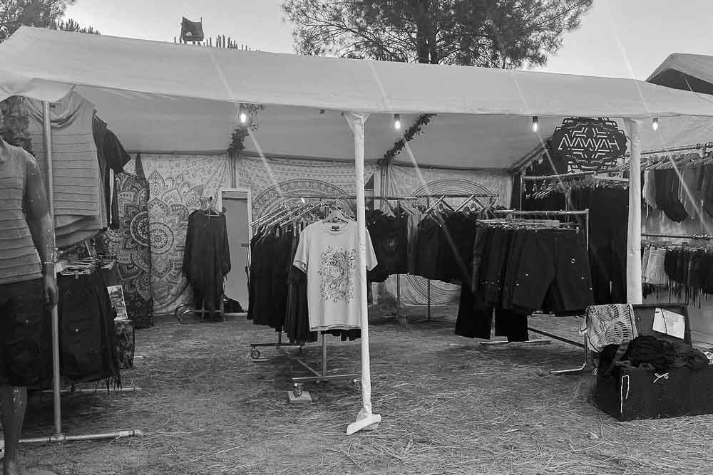 Avanyah's market stallstand displaying alternative clothing at an art fair, blending festival fashion with psychedelic trance vibes.
